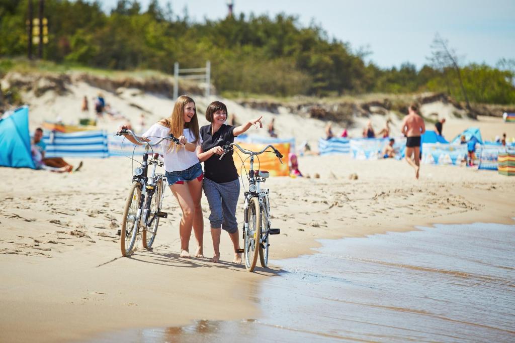 罗威Kormoran Medispa的两名女孩在海滩上骑着自行车