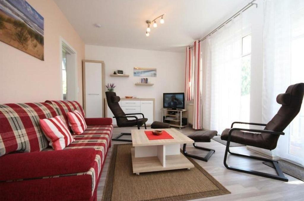 奥斯赛拜-屈隆斯博恩Strandschloesschen-Haus-II-WE-18-9723的客厅配有红色的沙发和椅子