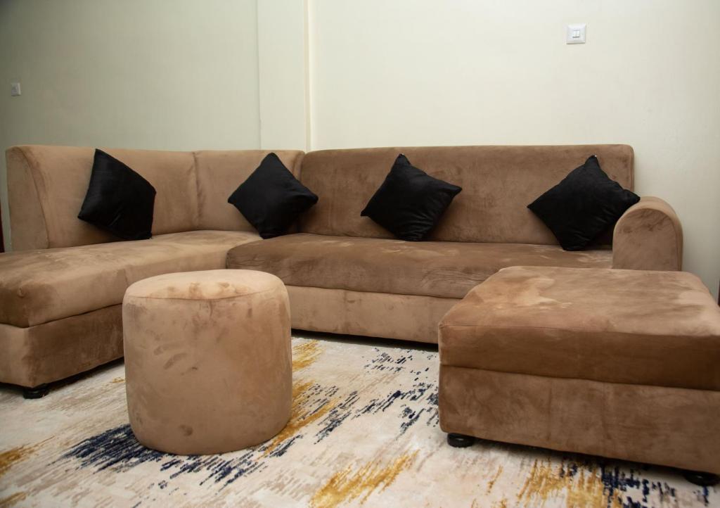 坎帕拉FG Homestay, Kampala Muyenga-Bukasa的客厅配有棕色沙发和2张搁脚凳