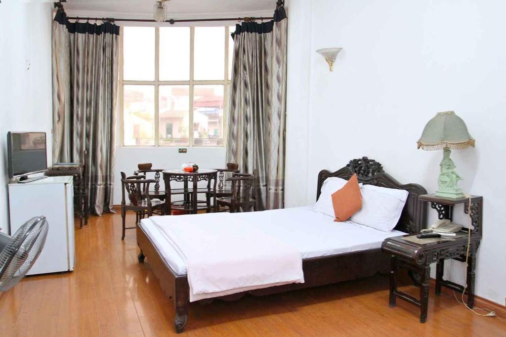 河内HOÀNG CƯỜNG HOTEL 15 Nguyễn Thái Học的一间卧室配有一张床和一张桌子及椅子