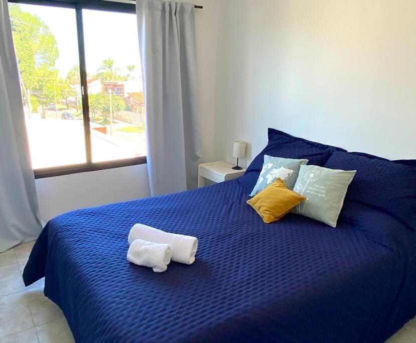 莫龙.Amplio y completo depto en Morón的一张蓝色的床,上面有毛巾,还有窗户