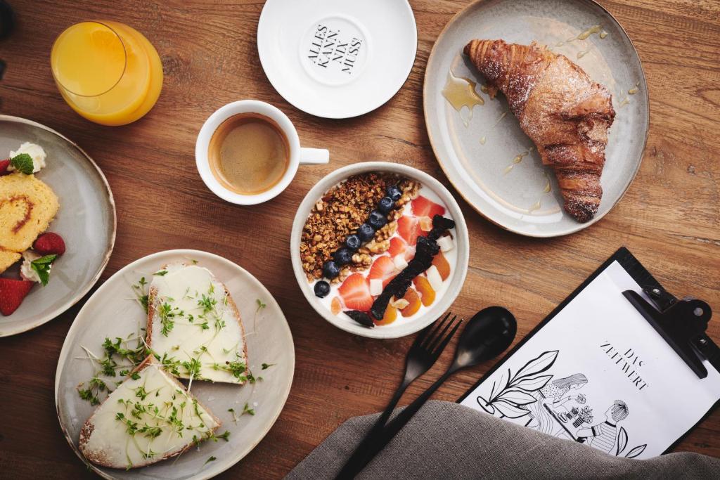德意志兰茨贝格Boutiquehotel DAS ZEITWERT的桌子上摆着几盘食物和一杯咖啡