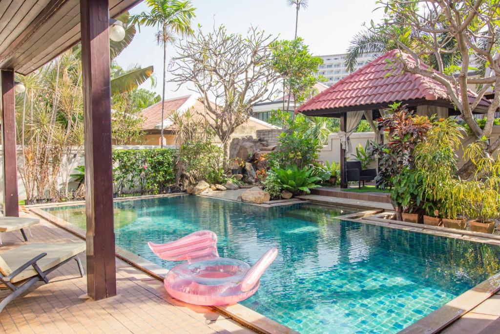 南芭堤雅Bali Haven 3BR PrivatePool Villa的一座房子旁的游泳池,配有两把椅子和一张桌子