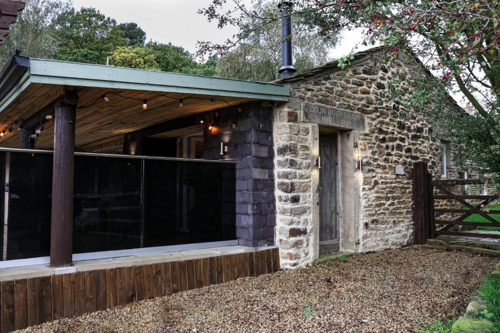 Old GlossopTanyard Barn - Luxury Hot Tub & Secure Dog Field Included的石屋,设有玻璃门和围栏
