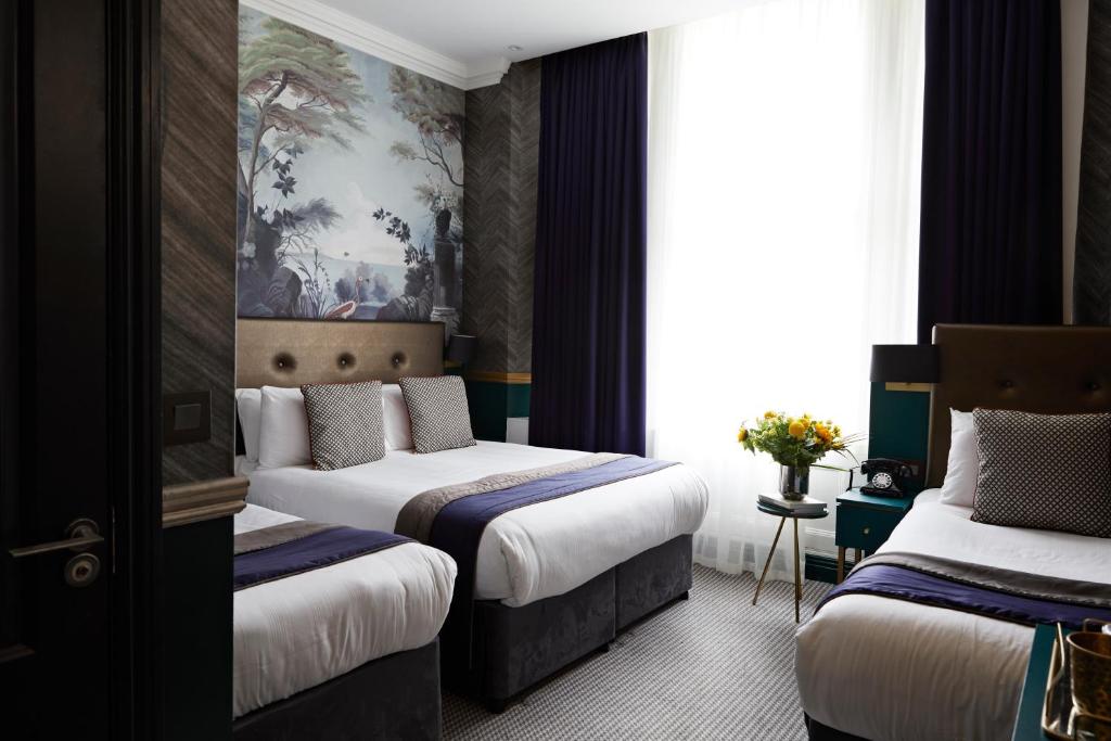 伦敦The Portico Hotel的酒店客房设有两张床,墙上挂有绘画作品