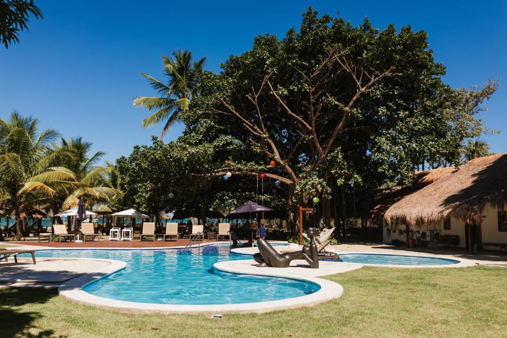 普拉亚多斯卡内罗斯班格多哥美罗若旅馆的一座带椅子的度假游泳池以及一座茅草屋顶建筑