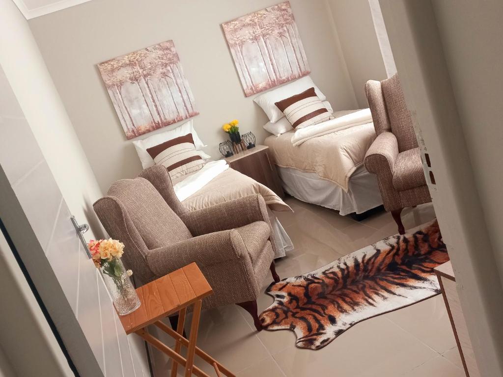 鲸湾港TALITHA'S SELF-CATERING ACCOMONDATION的客厅配有两张床和椅子