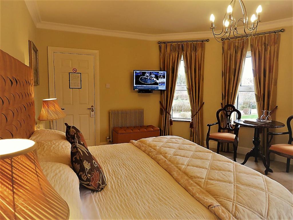 特拉利溪流庄园酒店的一间卧室配有一张床、一台电视和一张书桌