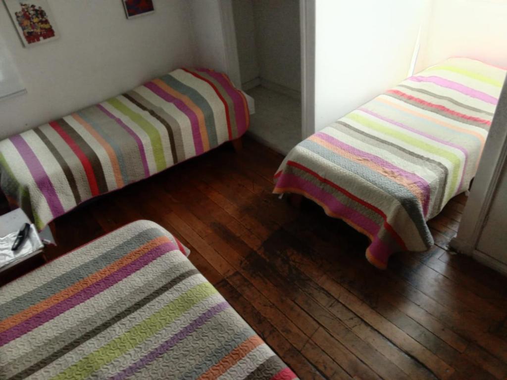 圣地亚哥Hostal Salvador的铺有木地板的客房内的两张条纹床