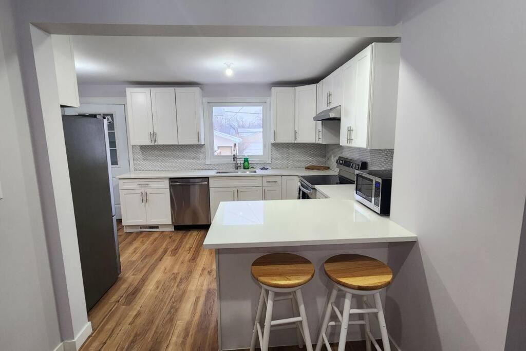 温尼伯St B. Living的厨房配有白色橱柜和带2张凳子的台面