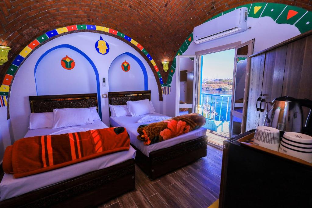 阿斯旺Nubian Popeye - Roof top - Nile View的一间带两张床的卧室,位于带窗户的房间内