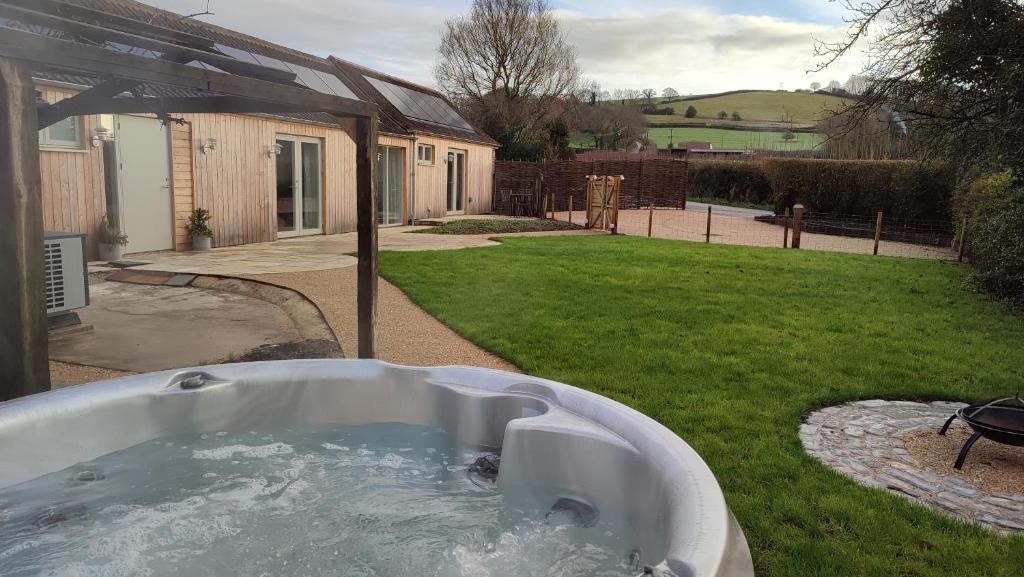 德斯利The Cow Byre - Cotswold retreat with hot tub的房屋的庭院里设有浴缸