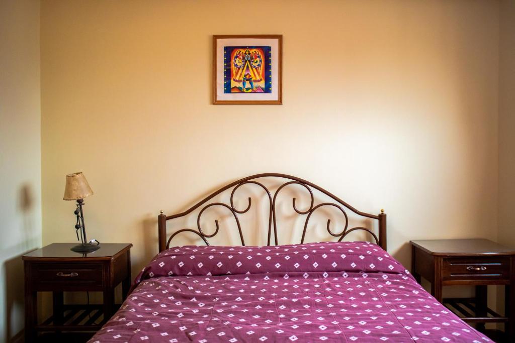 拉巴斯The Hidden House Hostel的一张带紫色棉被的床和墙上的照片