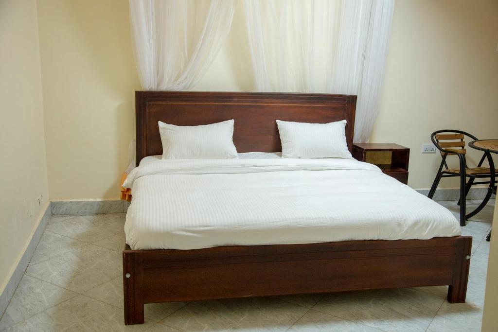 Eziana palm Hotels的卧室内的一张带白色床单和枕头的床