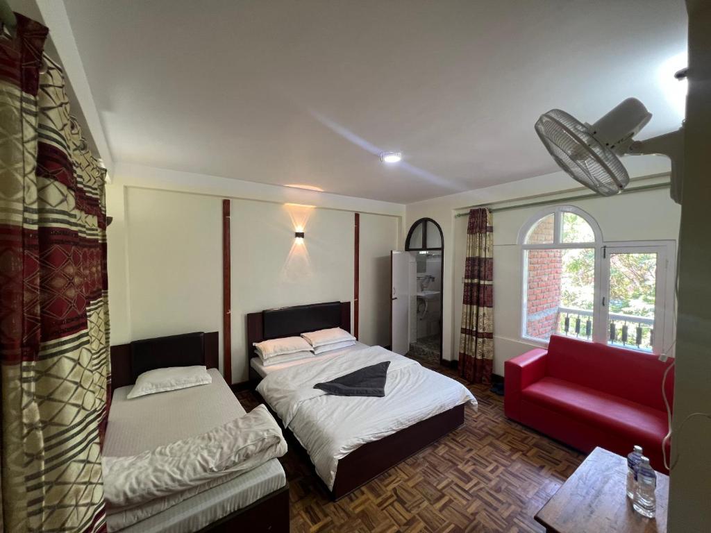 加德满都Hello KTM Hostel的一间卧室配有两张床和一张红色沙发