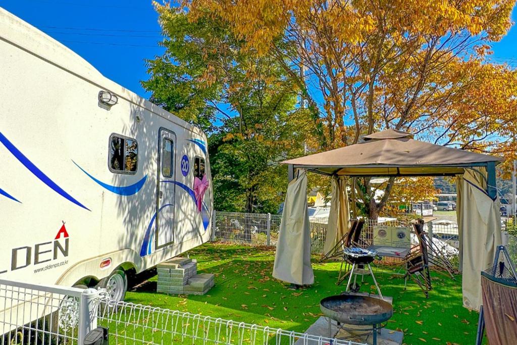 加平Gapyeong Olden Caravan & Pension - Pet Friendly的配有帐篷、桌子和雨伞的露营车