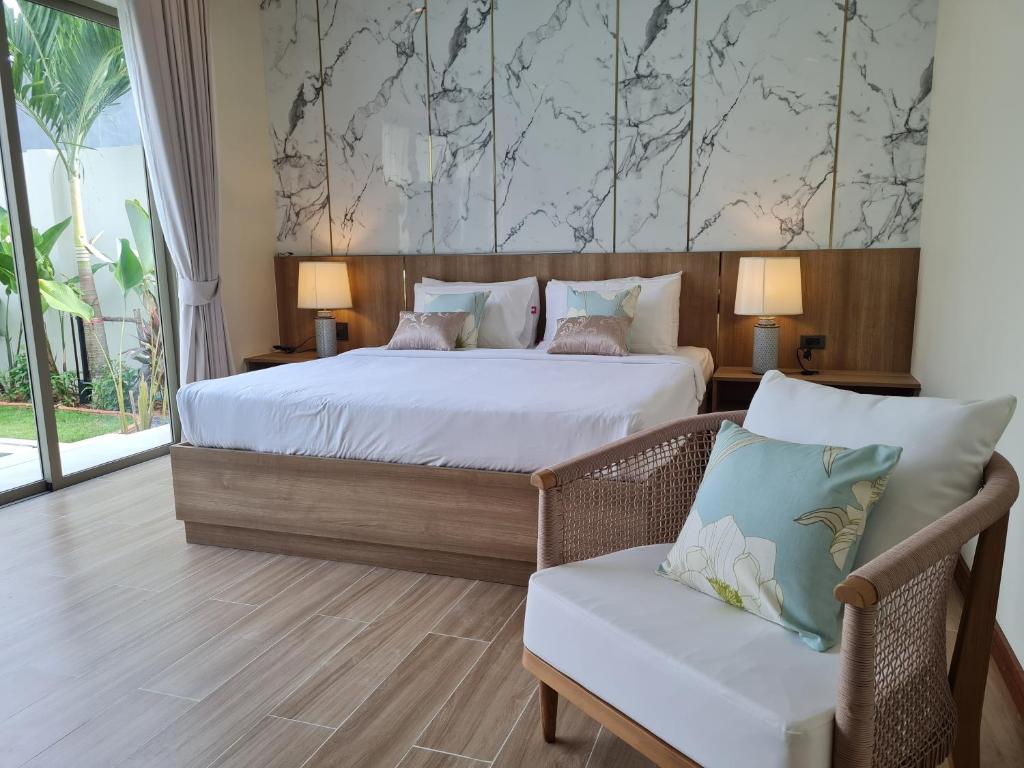 奈扬海滩普吉岛泳池别墅的一间卧室配有一张大床和一把椅子