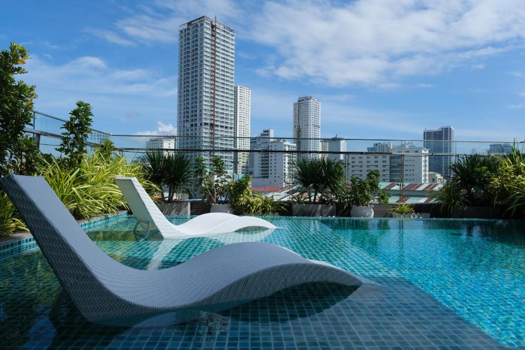 芽庄Em Oi Boutique Hotel的一座带两把白色椅子的游泳池,位于一座建筑的顶部