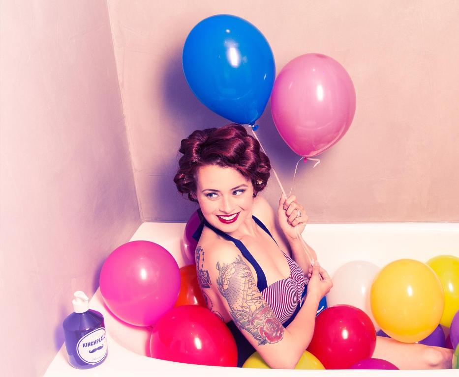 圣安东阿尔贝格科施广场膳食公寓酒店的坐在浴缸里拿着一束气球的女人