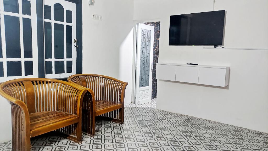 三宝垄Kost Harian Semarang Murah的一间房间,配有两把椅子和墙上的电视