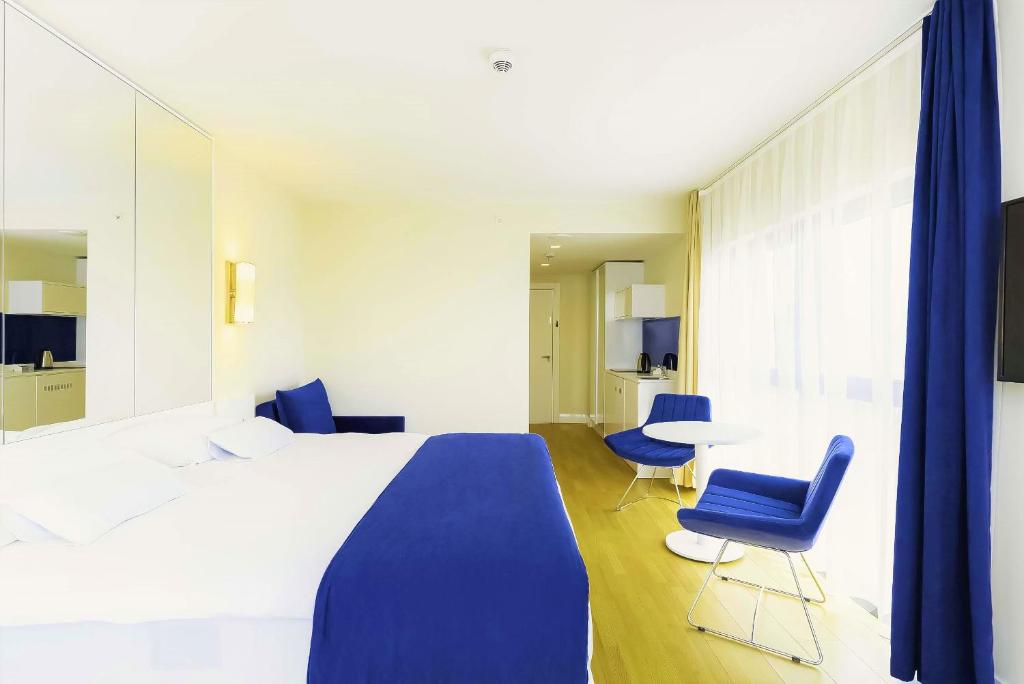 巴统Prestigious Sea View Aparthotel In Orbi City Batumi的一间卧室配有一张床、两把椅子和一张桌子