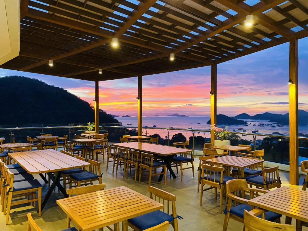 纳闽巴霍Zasgo Hotel的一间带桌椅的餐厅,享有日落美景