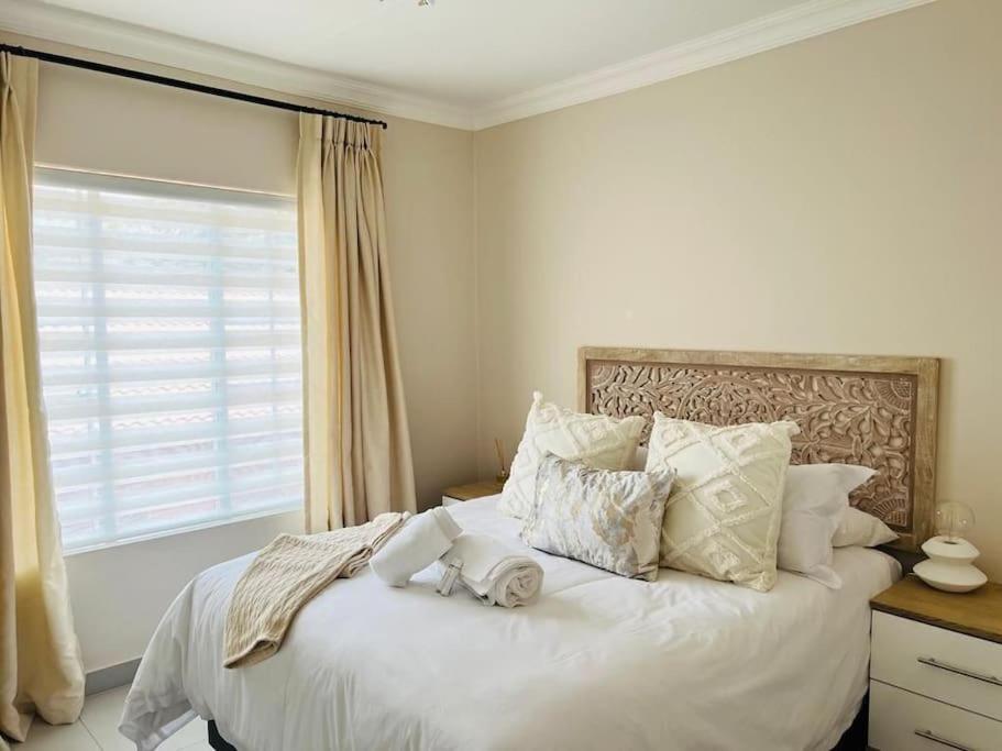 逊邱伦Wanderlust 2-bedroom Apartment的卧室配有带枕头的白色床和窗户。