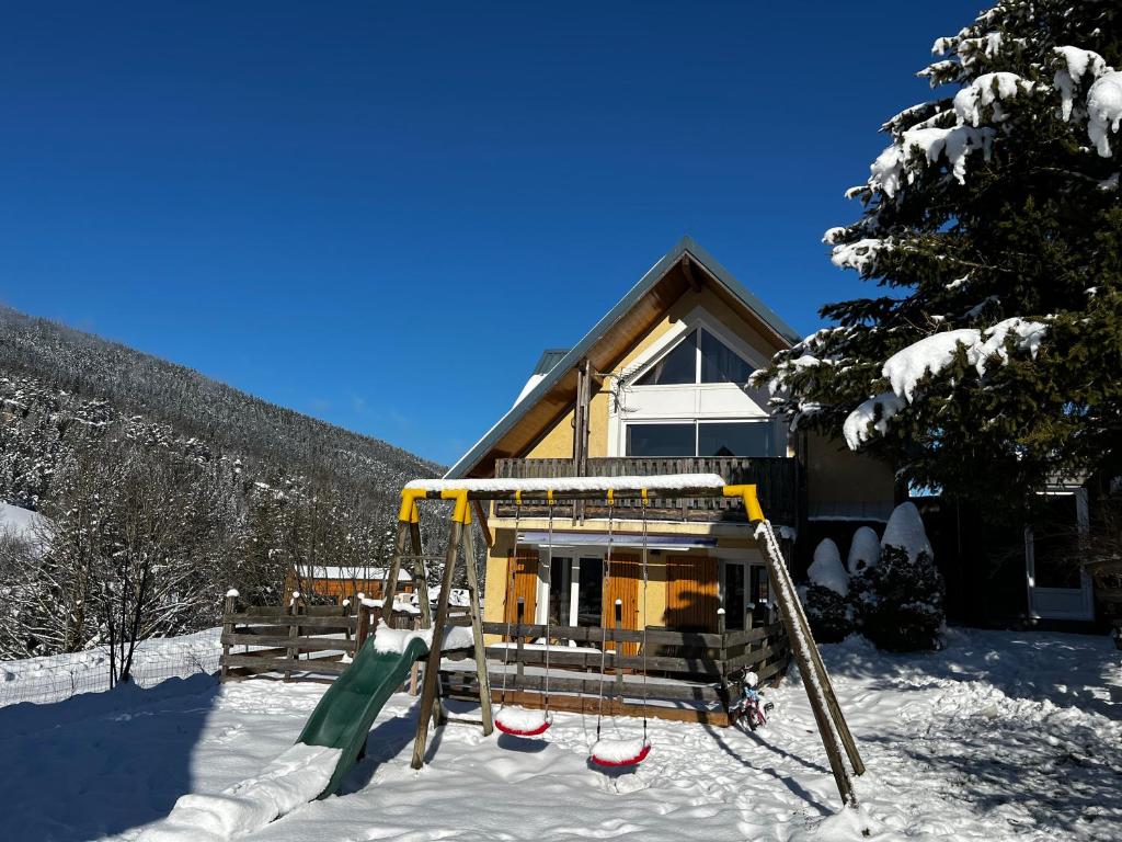 维拉尔-德朗Chalet de Montagne Villard de Lans的雪中房子前面的游乐场