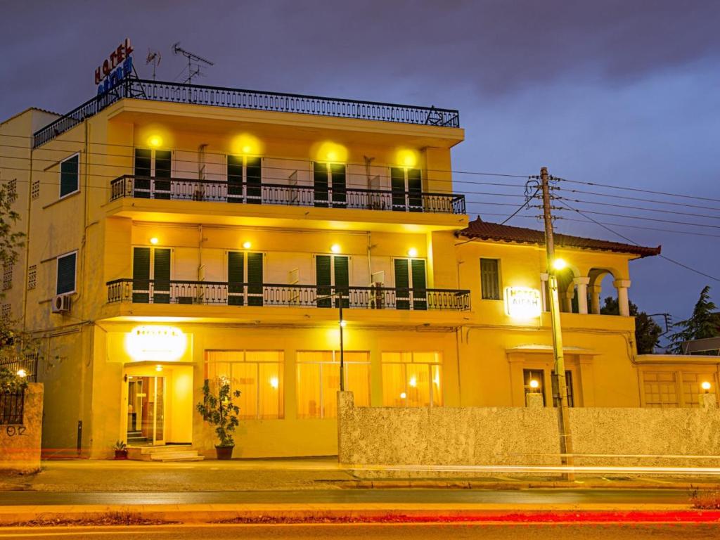 雅典阿格利酒店的一座黄色的大建筑,晚上设有阳台