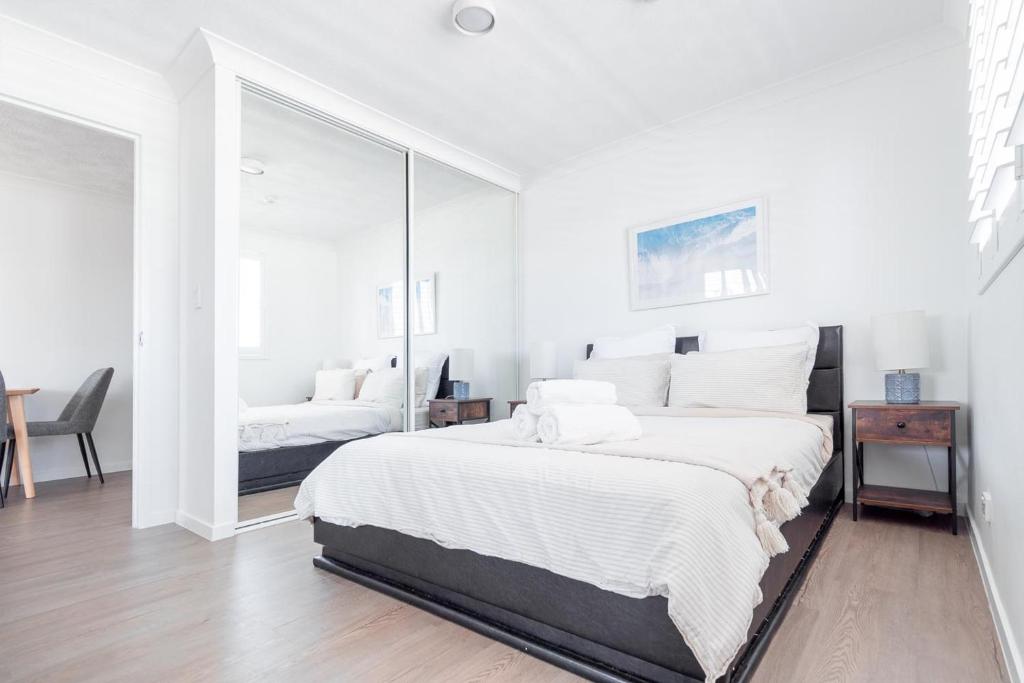 黄金海岸Freshly Renovated Modern Waterfront 1 Bedroom unit的白色卧室设有一张大床和镜子
