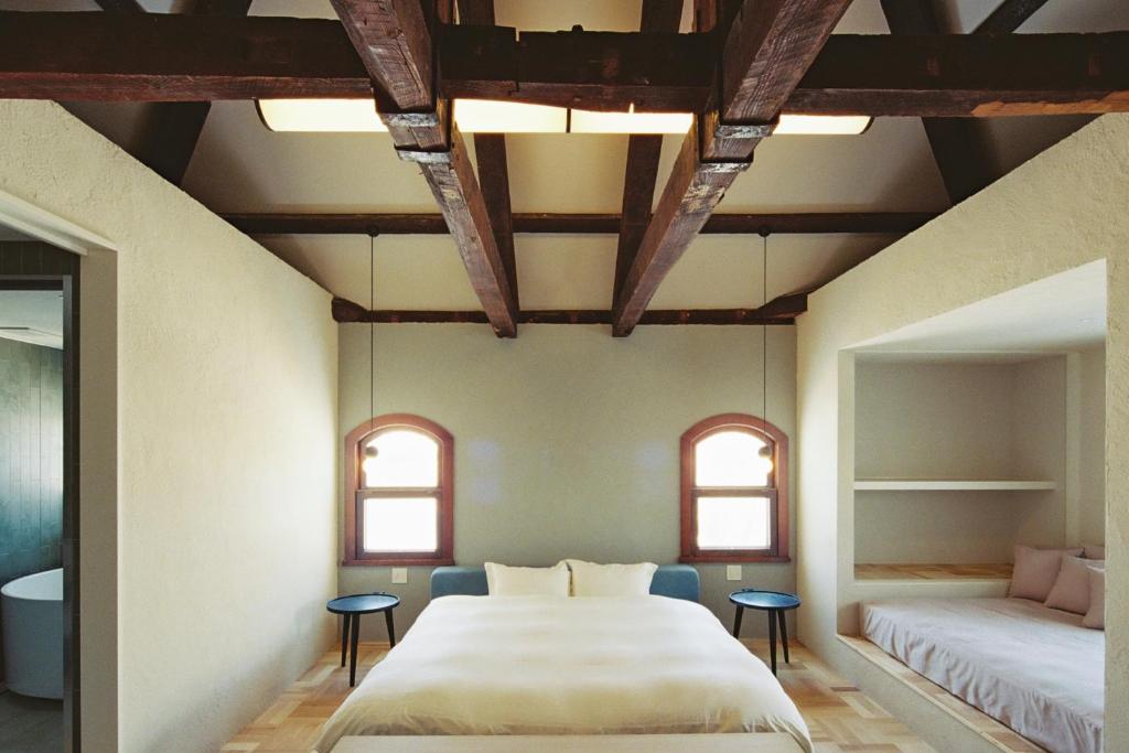 函馆Portside Inn Hakodate的一间卧室设有一张大床和两个窗户。