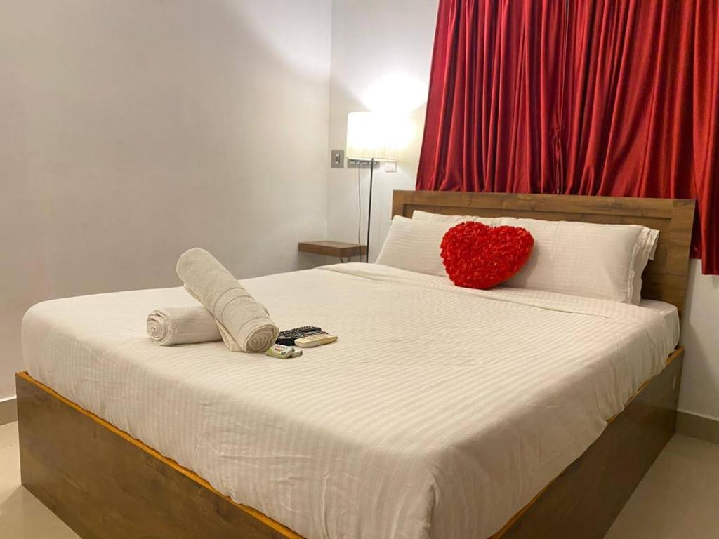 蓬蒂切里La Paradise Residency的一张带红色心枕和毛巾的床