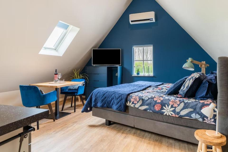 斯泰伦丹B&B Studio/Appartement Bij Zee的一间拥有蓝色墙壁的卧室,配有一张床和一张桌子