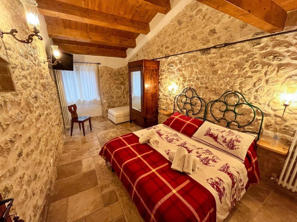 坎波迪焦韦B&B Casa Antonetti的一间石墙卧室,配有红色的床