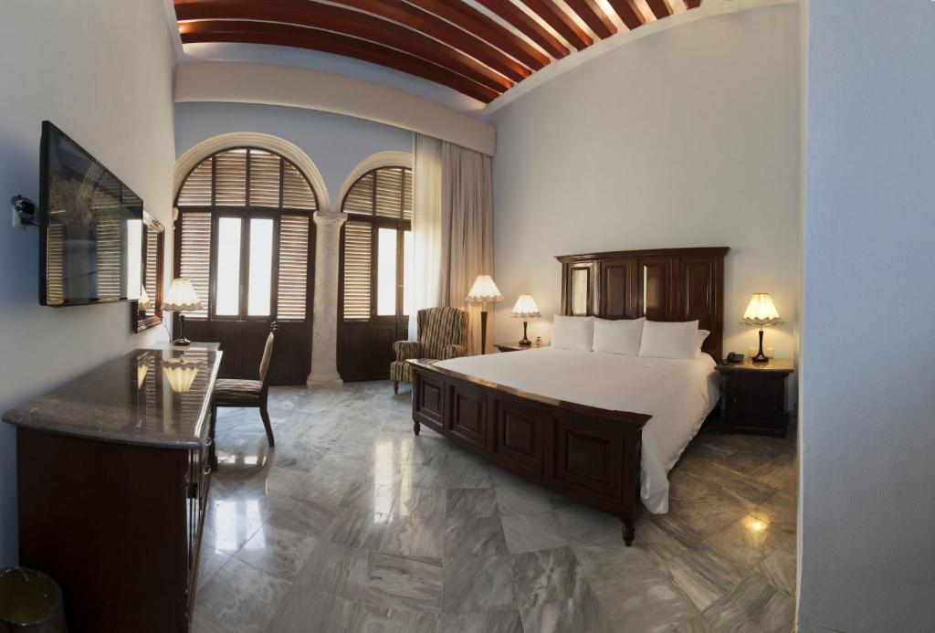 坎佩切坎佩切洛佩斯酒店的一间卧室配有一张大床和一张桌子及椅子