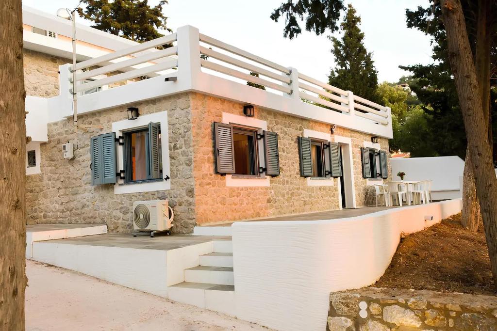 米尔泰Marialenas House - Stone House at Myrties Beach Kalymnos的砖屋,设有蓝色百叶窗和楼梯