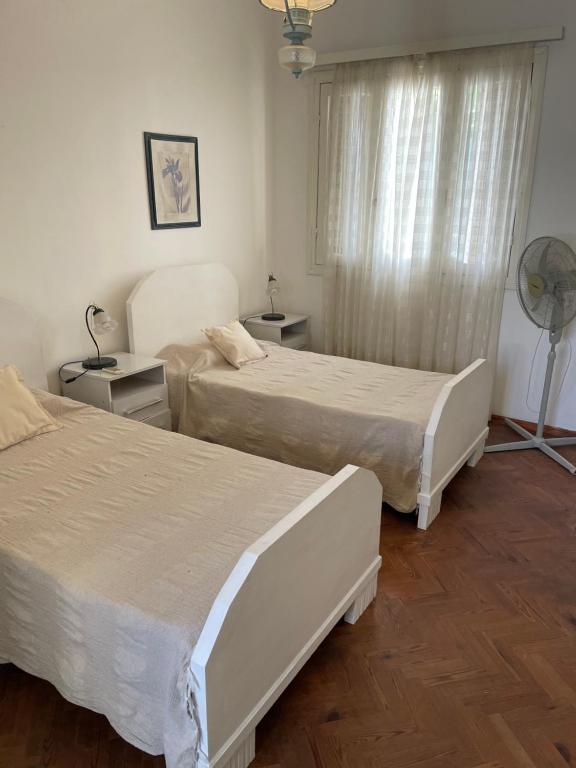 梅塞德斯Casa 1 habitacion的一间卧室设有两张床、风扇和窗户。