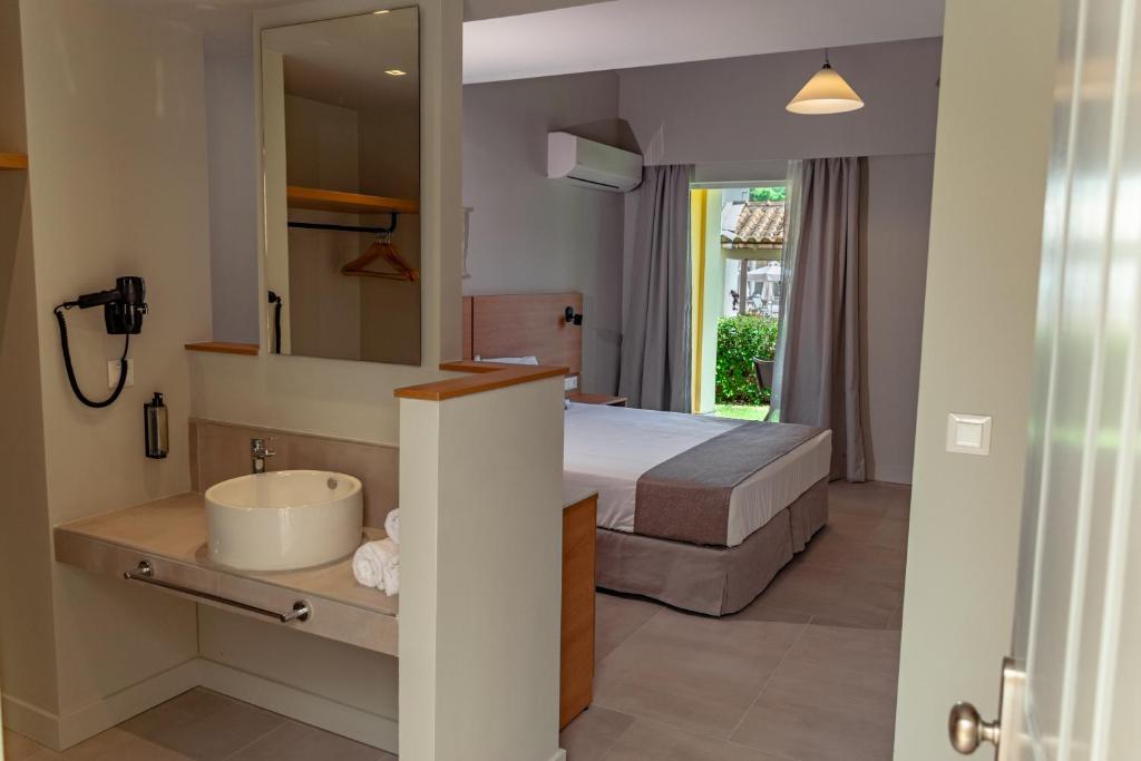 卡沃斯Olympion Village的一间卧室配有床、水槽和镜子