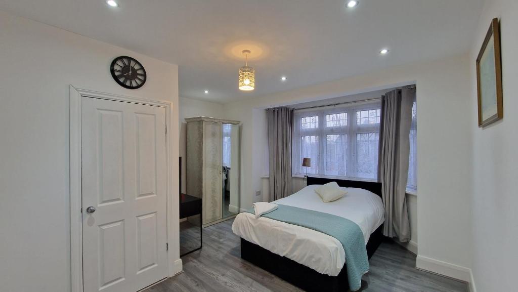 WansteadElegant 2-Bedroom Double En-Suite Flat - London的卧室配有一张床,墙上挂着一个钟