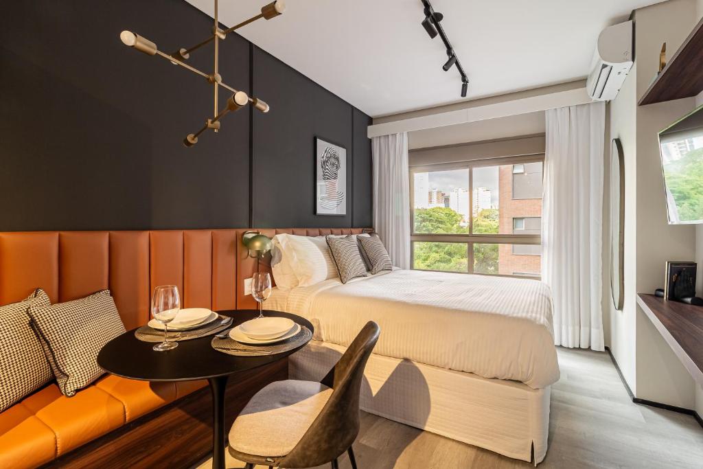 圣保罗Iconyc Charlie Hotel São Paulo - Soft Opening的一间卧室配有一张床、一张桌子和一个窗户。
