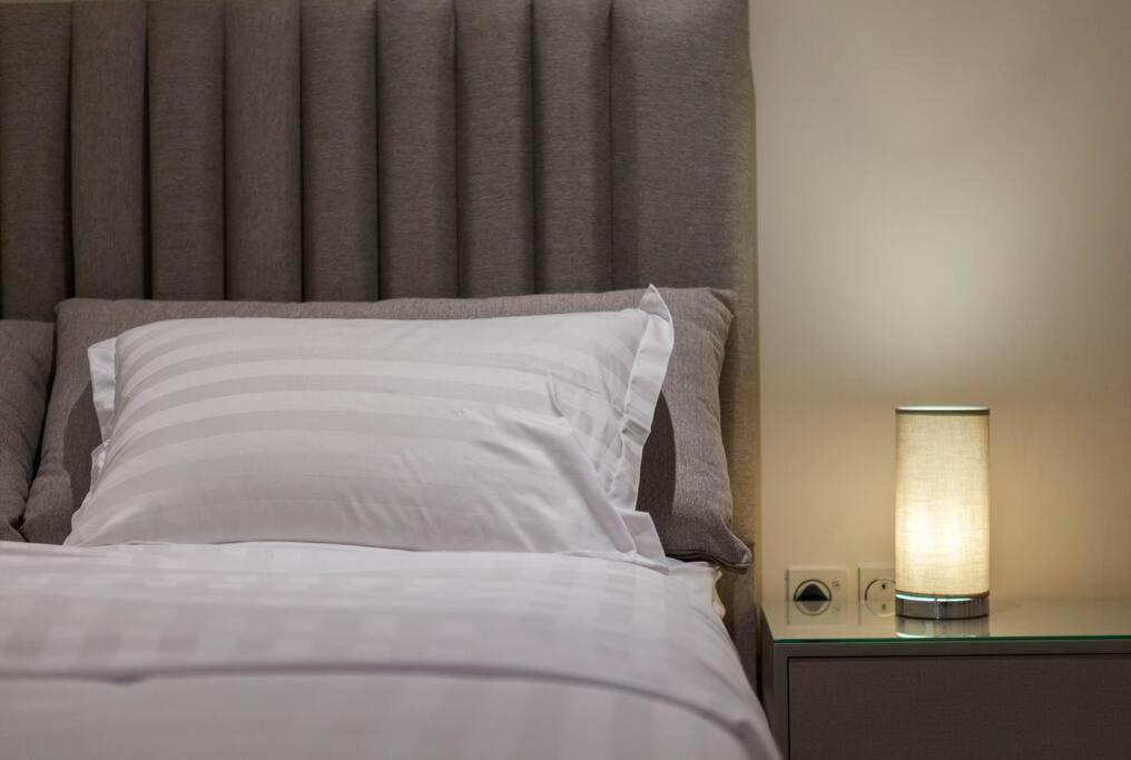 利雅德شقة انيقة وفاخرة بحي العليا Elegant and luxurious apartment Al-Olaya的一张带白色枕头的床和一张带台灯的桌子