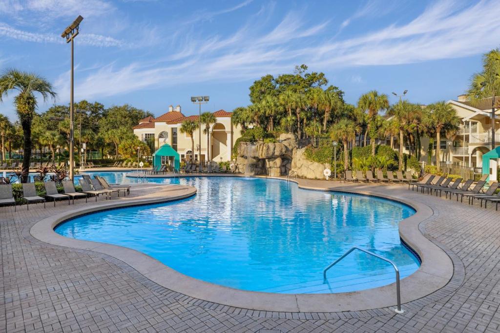 奥兰多Sheraton Vistana Resort Villas, Lake Buena Vista Orlando的一座带椅子和树木的度假村游泳池