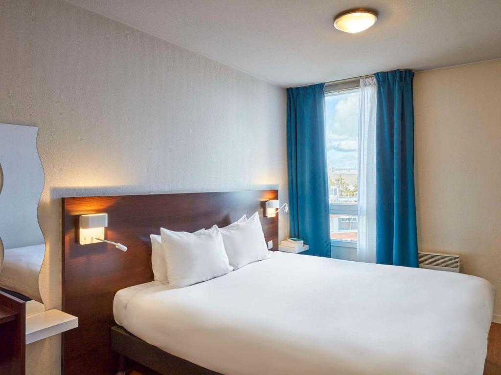 圣但尼巴黎圣但尼普莱耶尔阿德吉奥公寓式酒店的卧室设有一张白色大床和一扇窗户。