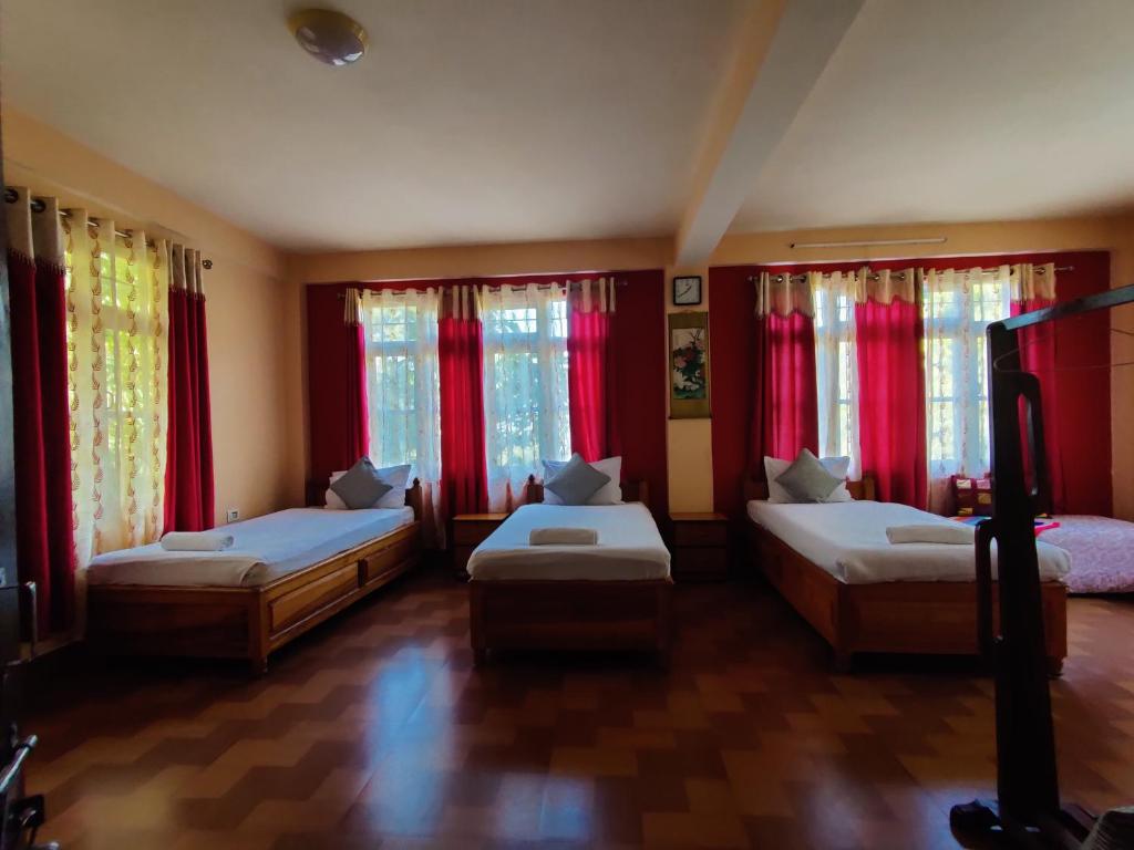 噶伦堡The Shire Kalimpong的一间卧室设有两张床和红色窗帘