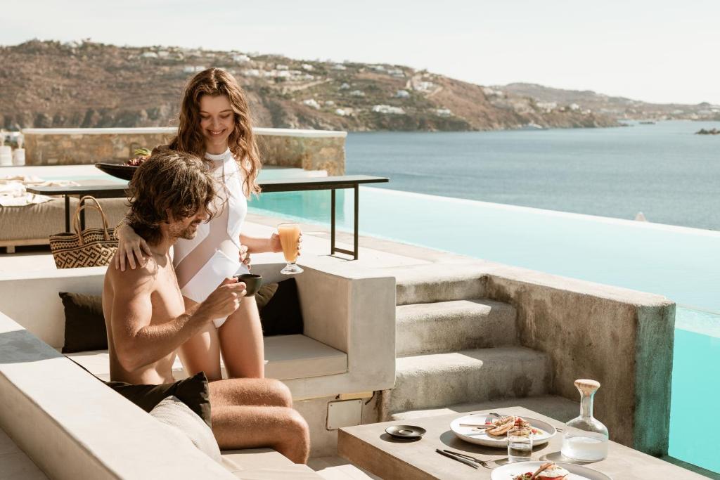 圣爱奥尼斯米科诺斯Casa Del Mar - Small Luxury Hotels of the World的坐在游泳池旁楼梯上的男女