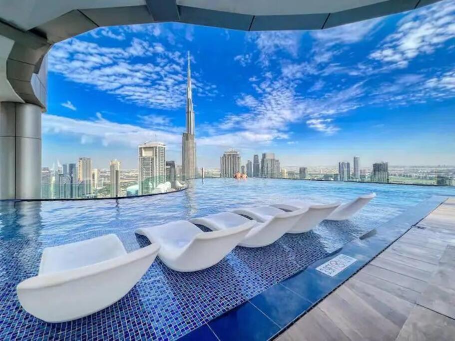 迪拜Luxurious one bedroom Apartment的城市天际线中央的带白色椅子的游泳池