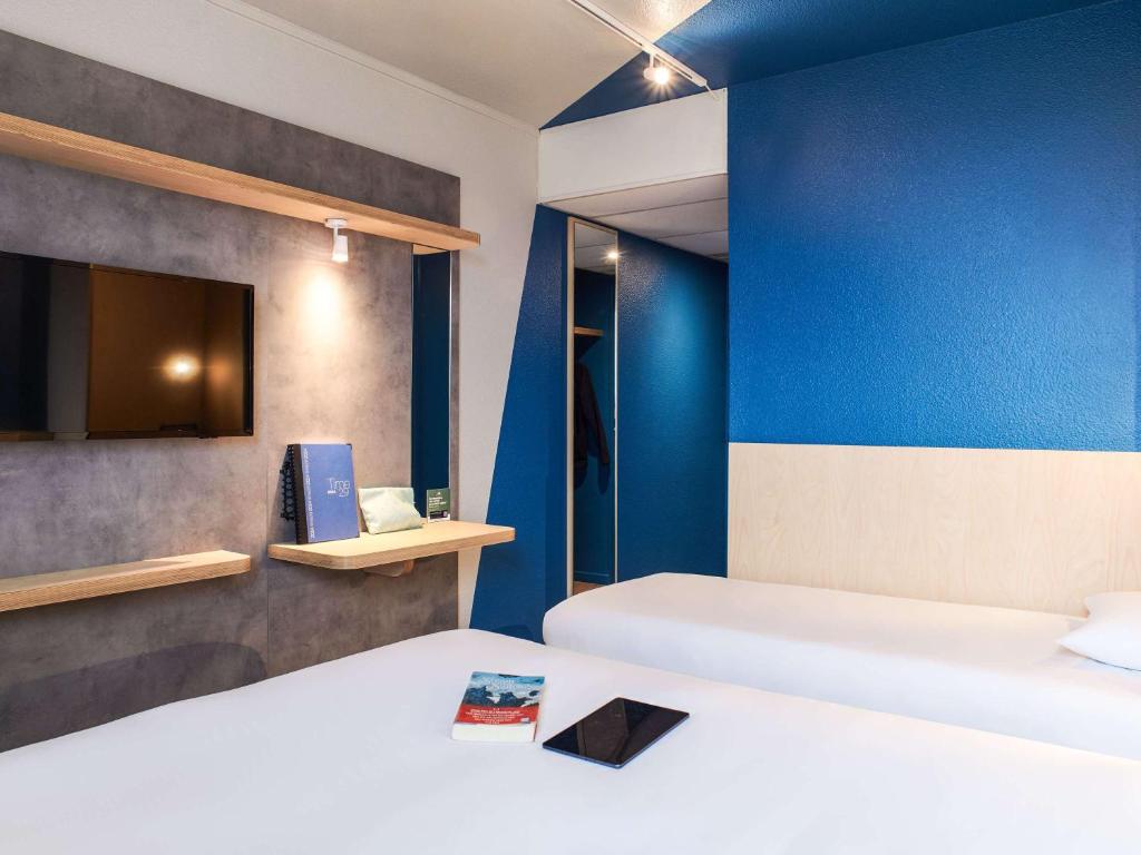 CouëronHôtel Ibis Budget Nantes Ouest Atlantis Couëron的一间设有两张床和蓝色墙壁的客房