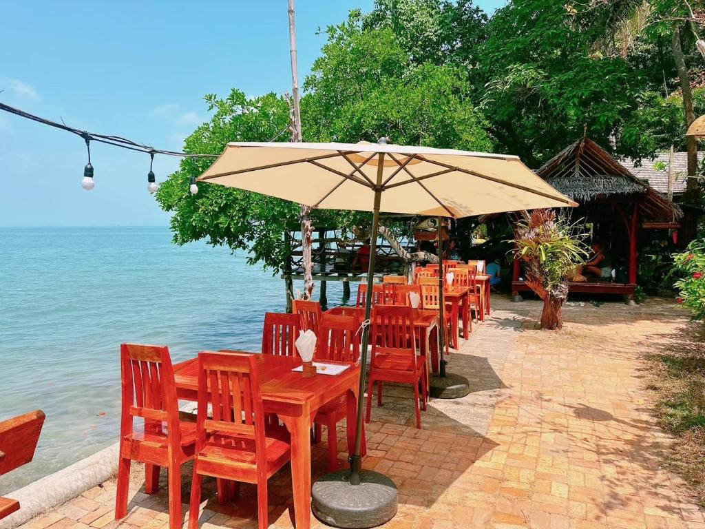 阁遥岛Sabai Corner Bungalows - SHA Extra Plus的一排桌椅和一把伞