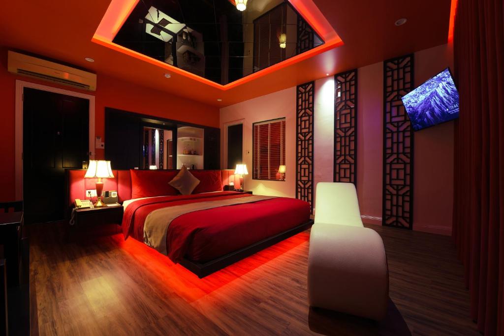 岘港Chiic House 3 - Khách sạn tình yêu的一间卧室配有红色的床和电视。