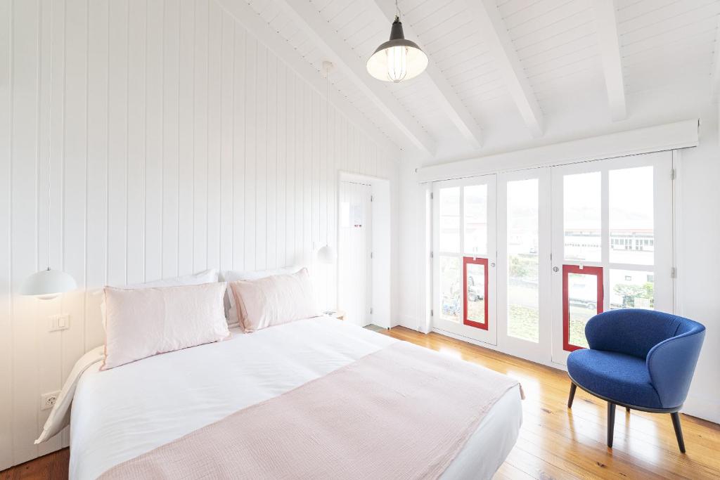 拉日什杜皮库Engenho Hostel的白色卧室配有床和蓝椅
